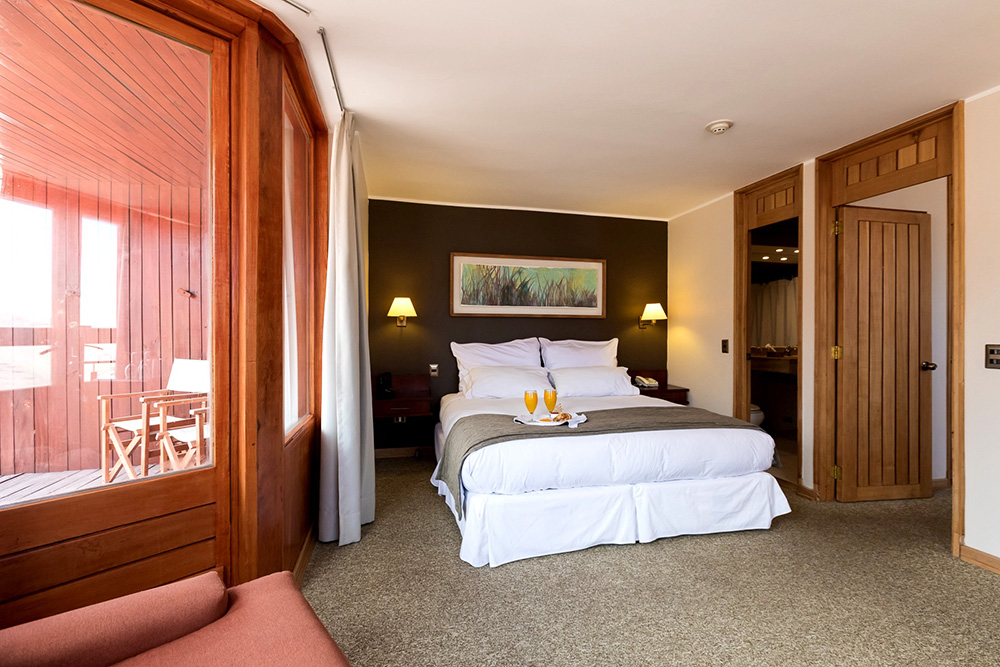King bed in hotel suite with balcony overlooking the ski slopes at Valle Nevado, Chile