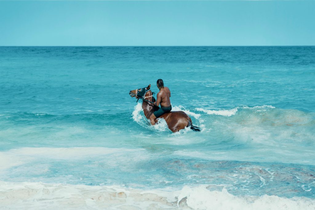 Man on horseback rides through surf off Providencials in Turks and Caicos.