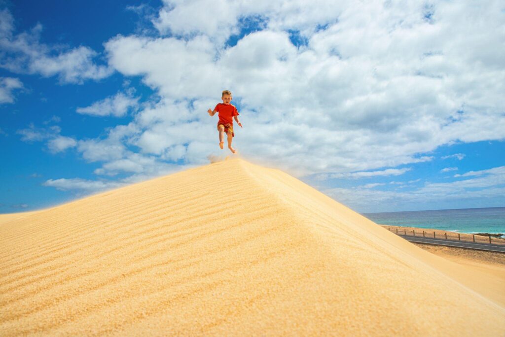 Boy surifng sand dunes in the Canary Islands.